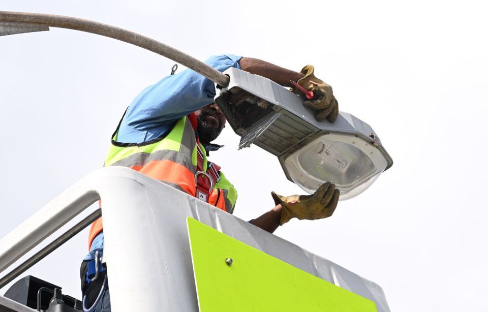 Technician repairing streetlight infrastructure as part of city efforts to improve electricity reliability and public safety