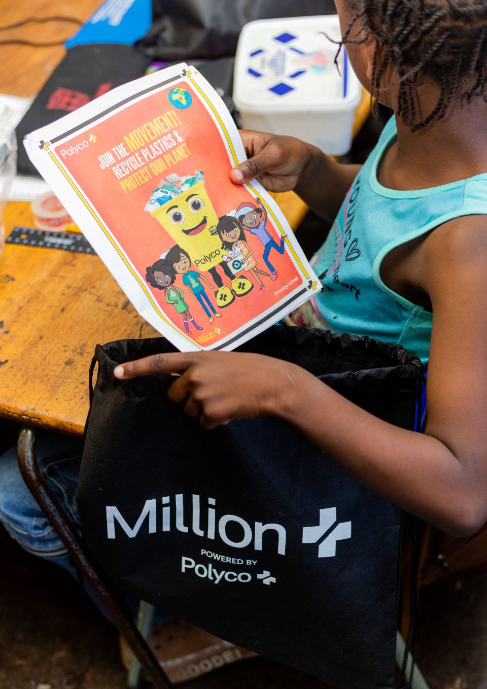 Grade 1 learner holding a Polyco recycling booklet during a classroom activity focused on plastic recycling and environmental education