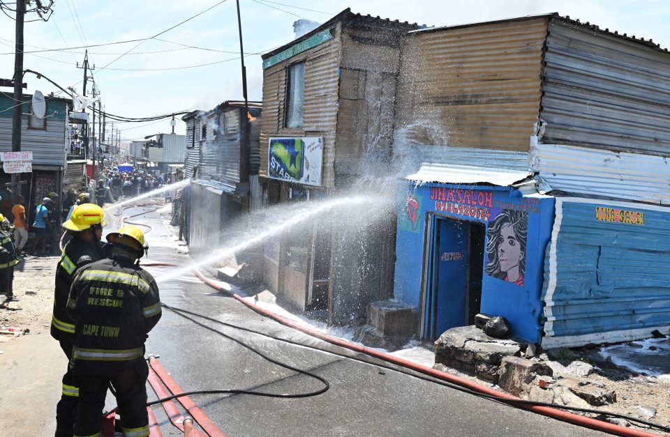 Cape Town firefighters extinguishing a fire in an informal settlement area using high-pressure hoses