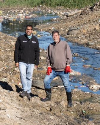 Community environmental volunteers stand beside the polluted Soet River during a clean-up and river restoration initiative in Cape Town.