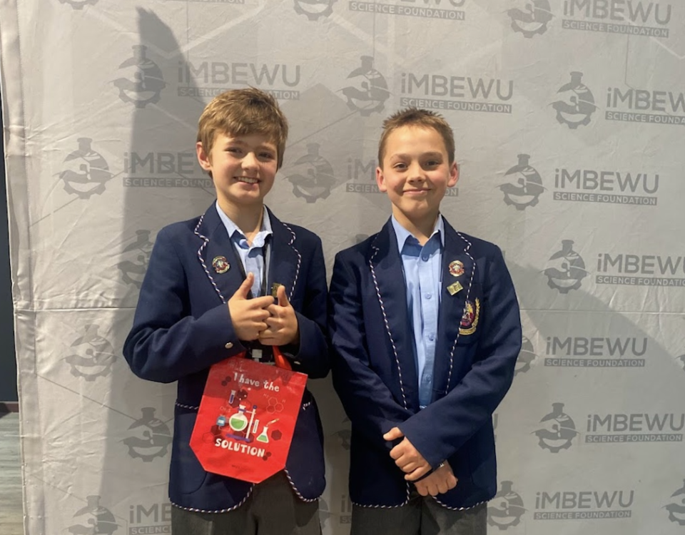 Two Grade 8 learners pose in school uniforms at the Imbewu Science Foundation event after earning recognition for their AI-driven classroom innovation project.