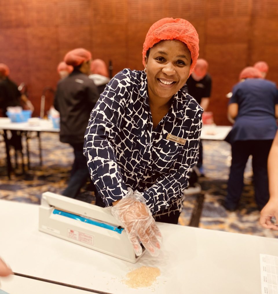 A Marriott International staff member participates in a meal-packing initiative, helping prepare nutritious food parcels for vulnerable children during a World Hunger Day community outreach event.