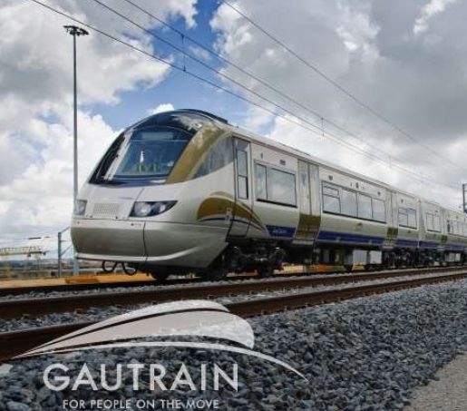 A Gautrain train travels along railway tracks under a partly cloudy sky in Gauteng.