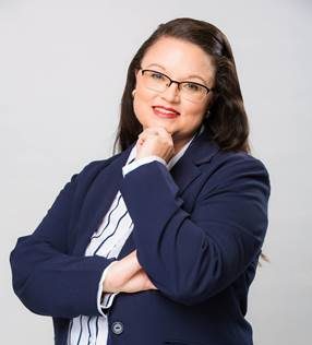 Professional portrait of a woman wearing glasses and a navy blazer.