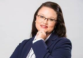 Professional portrait of a woman wearing glasses and a navy blazer.