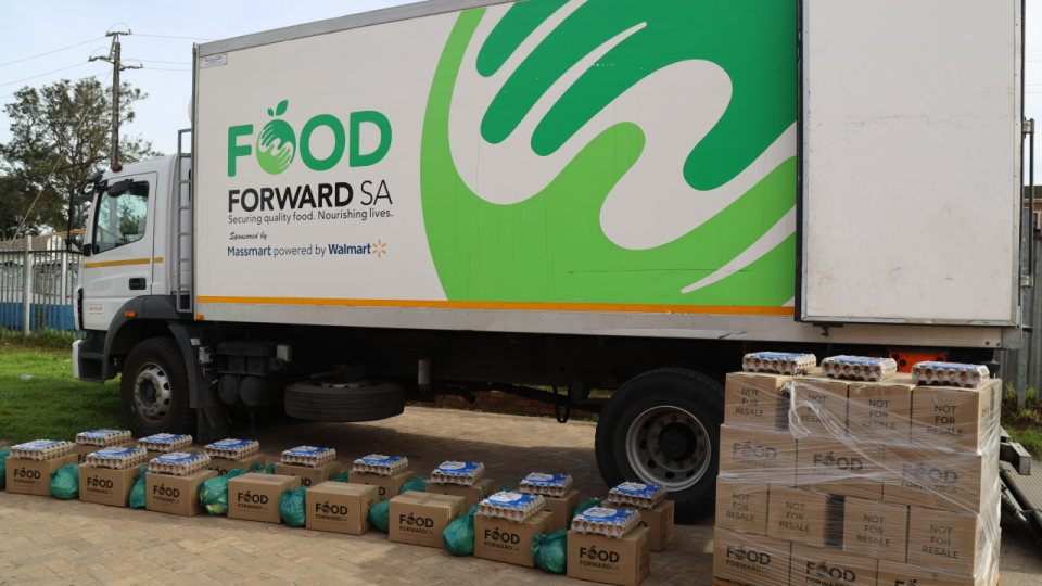FoodForward SA food parcels and eggs prepared for distribution beside a FoodForward SA delivery truck.