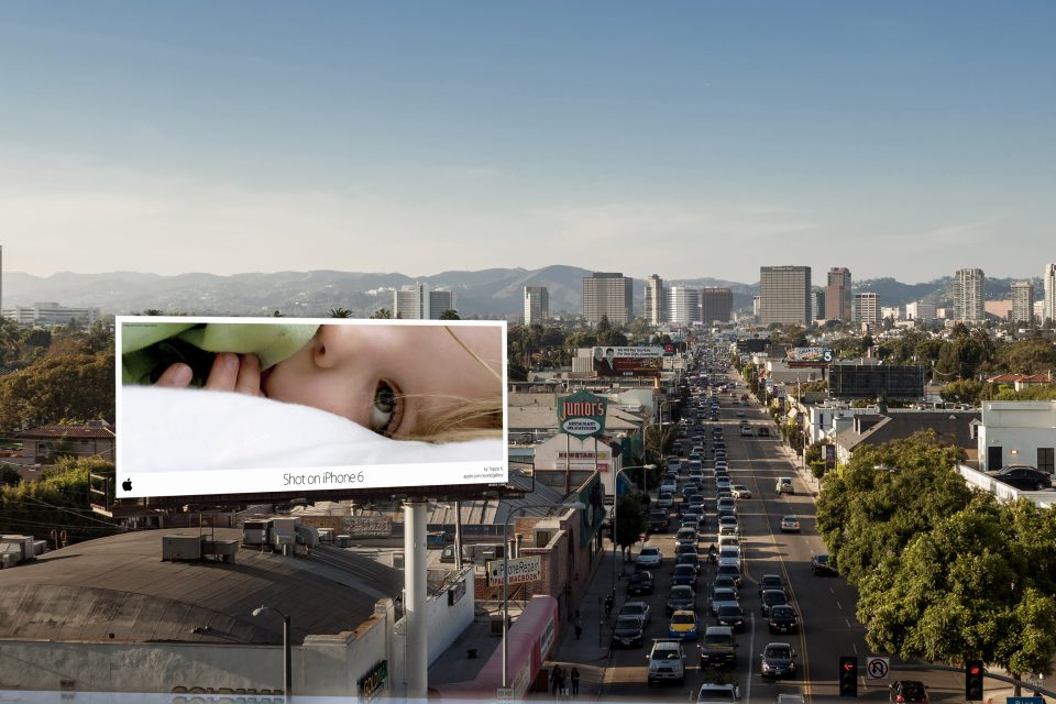 Apple’s Shot on iPhone campaign displayed on a large billboard overlooking a busy city street.