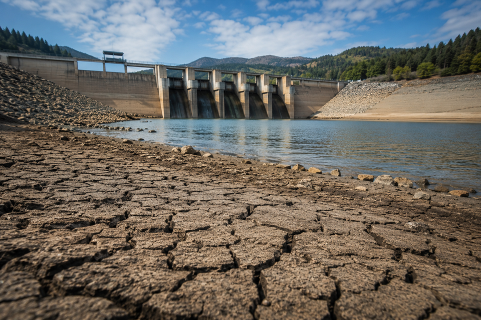 Dam and reservoir with exposed dry ground highlighting the importance of water conservation and responsible water use.