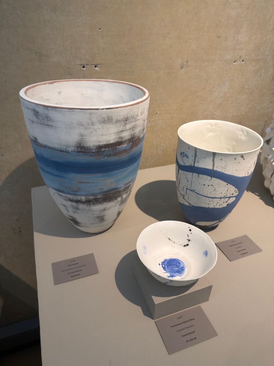 Three contemporary blue-and-white ceramic vessels displayed as part of a South African ceramics exhibition.