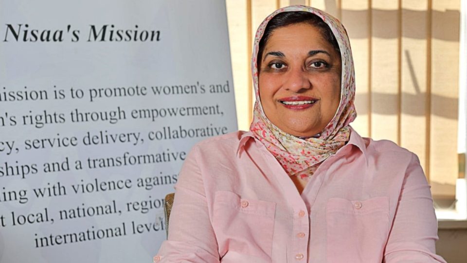 Dr Zubeda Dangor, clinical psychologist and GBVF specialist, seated in front of a Nisaa Institute for Women's Development display.