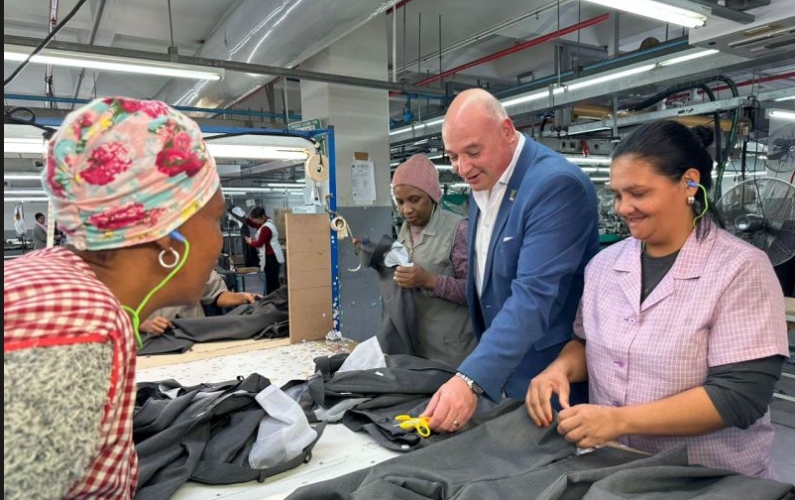 Clothing and textile manufacturing workers engage with a City of Cape Town representative during a factory visit.