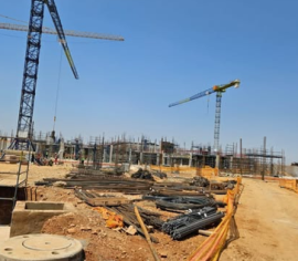 Construction site showing cranes and structural works underway for a major infrastructure development in South Africa.