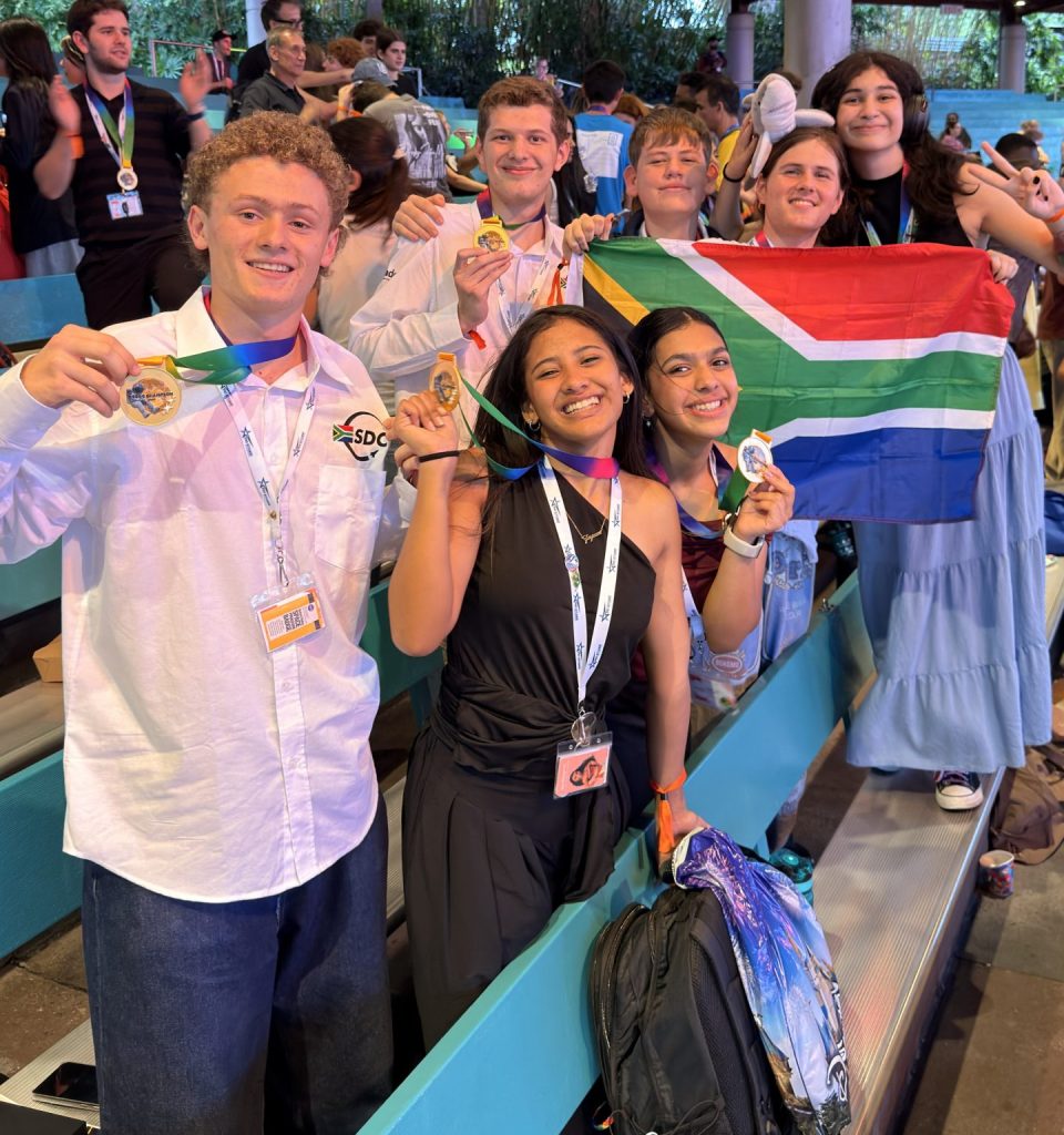 South African high school learners celebrate their international space design competition victory while holding medals and the South African flag.