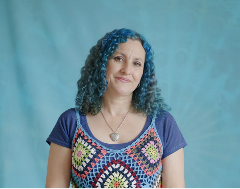 Portrait of Heartsong Collective founder Lynne Poulsen against a blue background.