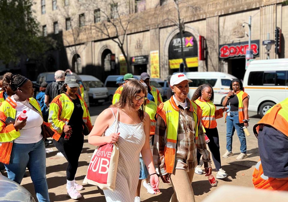 Participants and JICP programme workers walk through Johannesburg’s inner city during an anniversary activation highlighting regeneration, employment and community stories.
