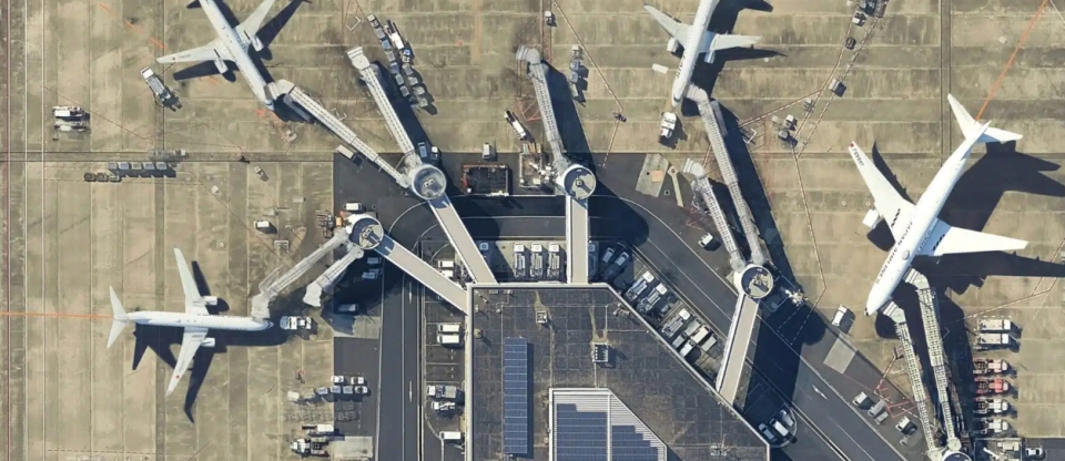 Aerial view of a busy international airport terminal with multiple passenger aircraft positioned at boarding gates.
