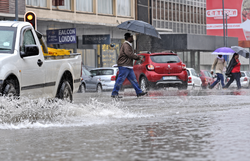 Pedestrians and motorists navigate a flooded urban road during heavy rainfall in KwaZulu-Natal.