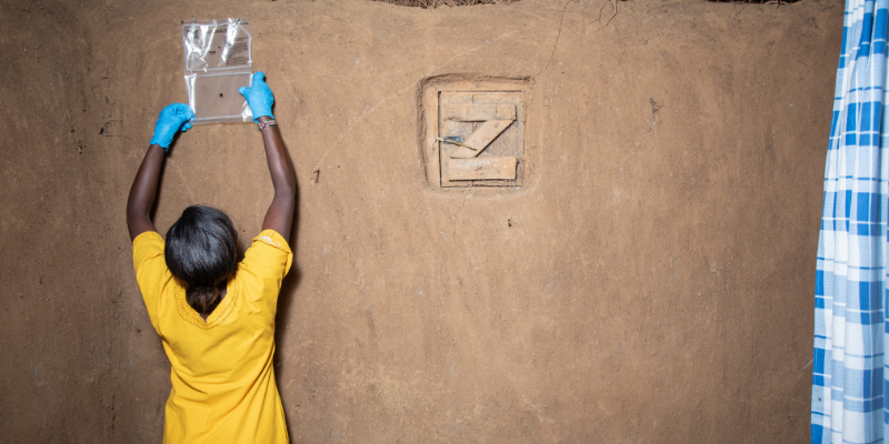 Community health worker installs a spatial emanator inside a home as part of malaria prevention efforts.