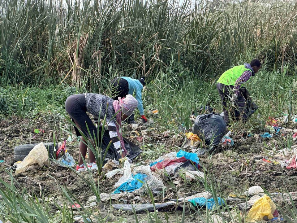 Community workers remove illegally dumped waste during a clean-up along the Soet River in Strand, Cape Town.