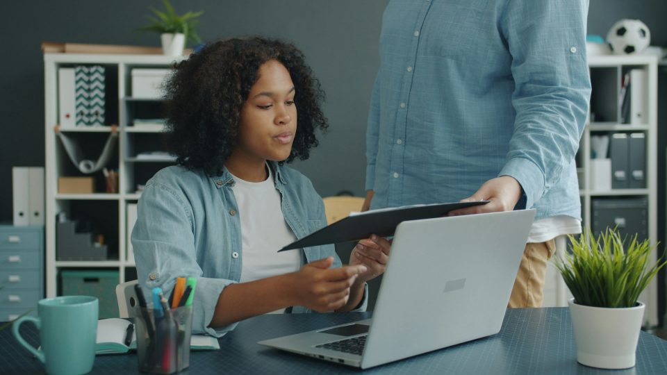 A journalist works on a laptop while reviewing documents, representing the digital transformation of independent and community newsrooms in South Africa.