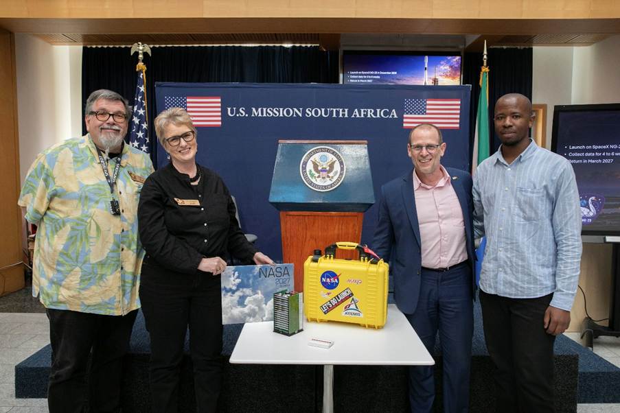 Four representatives pose alongside NASA-branded research equipment at the U.S. Mission South Africa during preparations for the Rooibos in Space project.